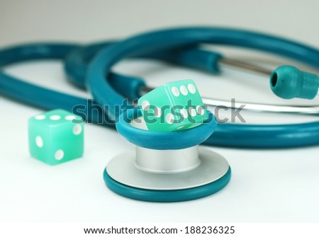 A Doctors Pink stethoscope with two aqua colored dice with white spots dice placed next to it, asking the question, do you gamble with your health.