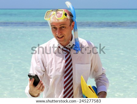 A Business man caught out on on a gorgeous tropical island, dressed in business attire holding his mobile phone in one hand with his flippers in the other and wearing a snorkel, should he answer that.