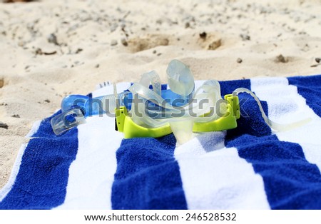 A yellow snorkel placed on a blue and white towel on the beach, asking the question are you ready for your holiday