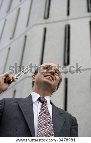 Businessman outside his office in the Central Business District, with a tuning fork held to his ear, indicating are you in tune with your business or its needs?