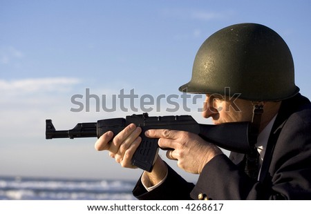 Businessman with a rifle aiming it at the beautiful ocean horizon, wearing a military green iron helmet, asking the question are you in the firing line?