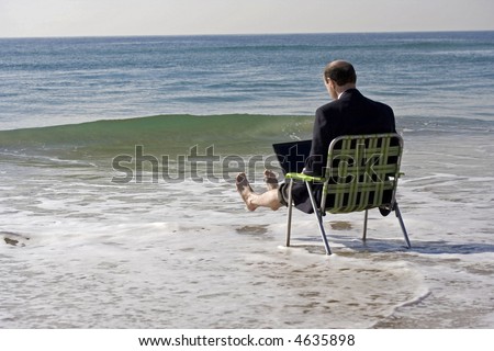 Businessman, in business clothes, under a colored umbrella at the beach, sat with his legs up in the air as the waves crash around him
