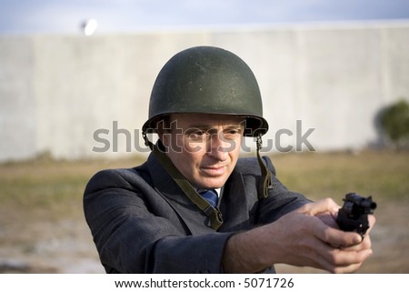 Businessman with a gun aiming it t you, wearing a military green iron helmet, asking the question are you in the firing line?