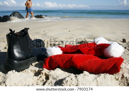 Father Christmas on Boxing Day at the beach, after the busiest night of the year, showing his hat, clothes and him walking  on the beach in his swimmers and the ocean in the background