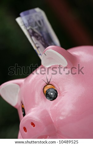 Pink piggy bank with a bank note about to pushed into the savings hole