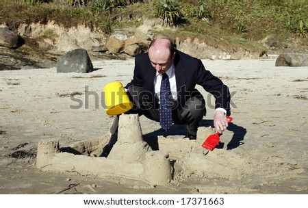 Businessman on the beach building sandcastles, but really thinking about building his own business empire.