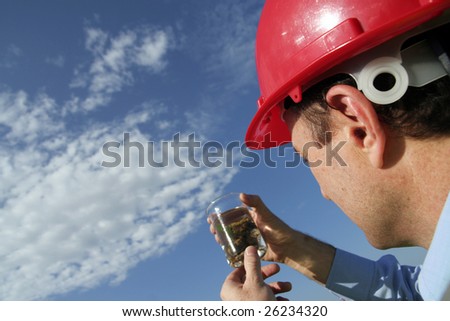 An environmental engineer examining a plant sample showing the beautiful blue sky, wearing a red safety helmet