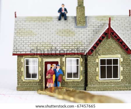 A bank manager sat on top of a couples house, who are about to walk away on the path of debt, signified by the path of gold coins leading away from their house of dreams.