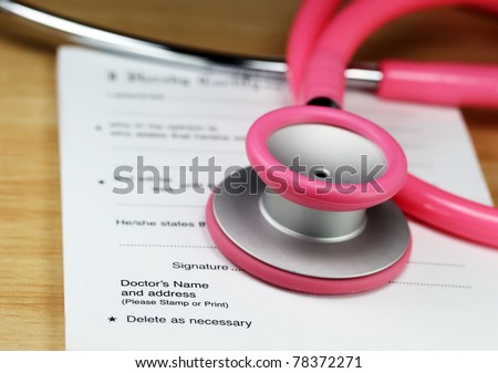 A female doctors desk showing a pink stethoscope and sick certificate pad, both resting upon the doctors wooden desk.