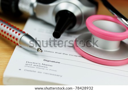 A female doctors desk showing a pink stethoscope, pen, and otoscope and sick certificate pad.