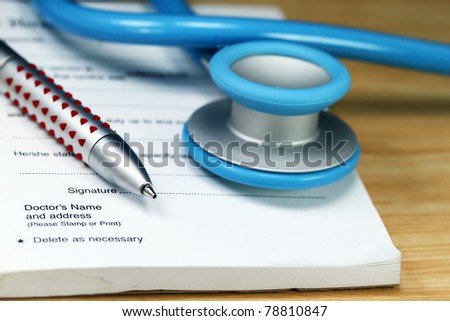 A  doctors desk showing a lightr blue stethoscope, pen and sick certificate pad.