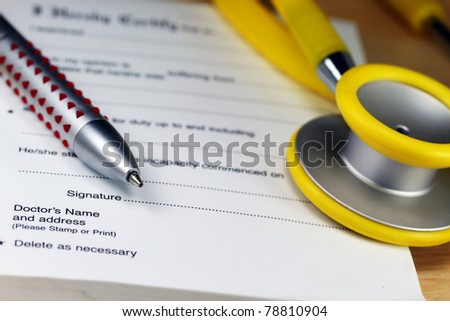 A doctors desk showing a yellow stethoscope, ball point pen and sick certificate pad.