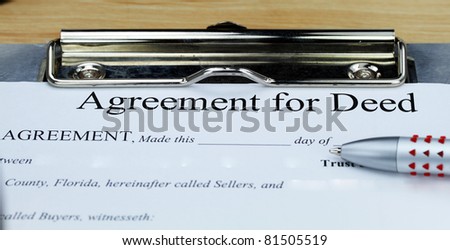 An agreement for a deed document on a clip board with a pen, ready for the client to complete.