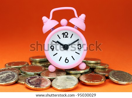 A pink alarm clock placed on some golden coins with an orange background, asking the question how long before your investment matures?