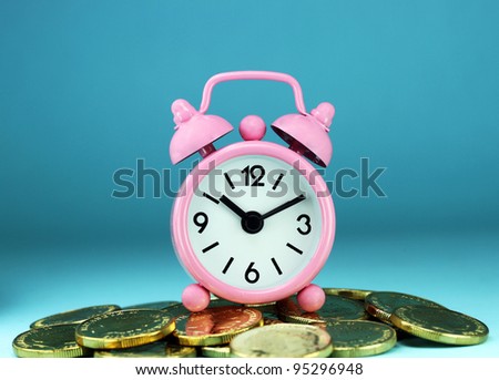 A pink alarm clock placed on some golden coins with a light blue background, asking the question how long before your investment matures?