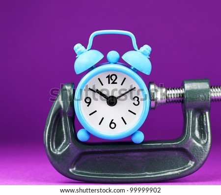 A light blue alarm clock placed in a Grey clamp against a pastel purple background, asking the question do you manage your time effectively.