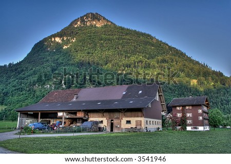 house and barn in Switzerland beneath a hill lit by morning light, HDRI