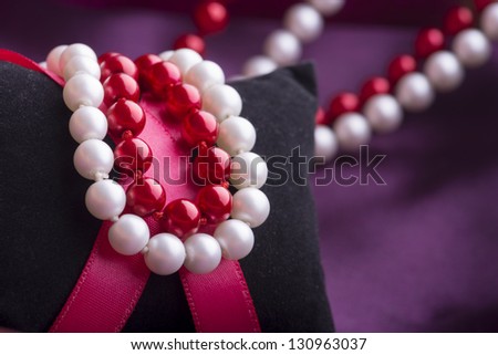White and Red Pearl Necklace over Purple Silk Fabic