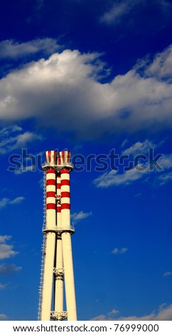 Chimney with red circle under blue sky on the factory