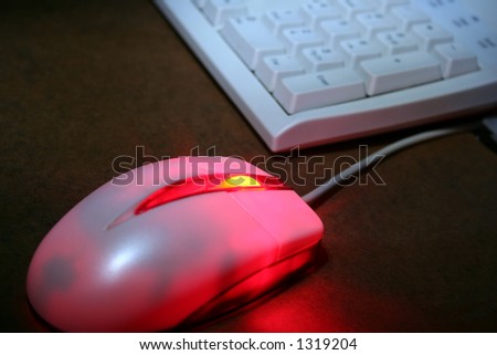 An optical mouse glowing red with keyboard in the background.