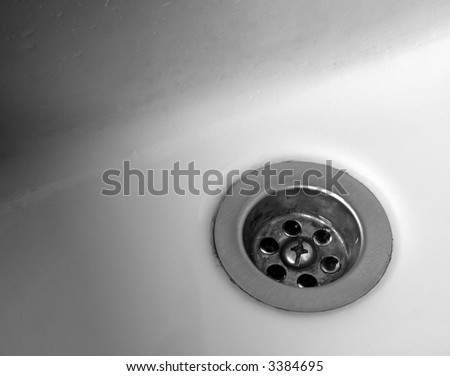 The drain of a porcelain bathroom sink in grayscale.