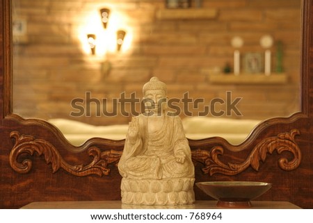 Buddha sits on mirrored coat rack, living room in background.
