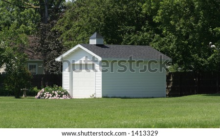 Back yard storage shed with garage door and vinyl siding - stock photo