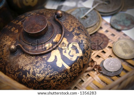 Vintage Chinese teapot and coins.  The golden Chinese word on the pot means ??good fortune?? and ??lucky??.