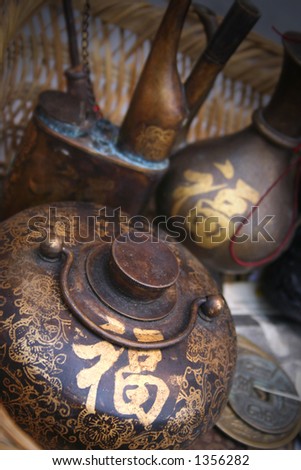 Vintage Chinese teapot and coins.   The golden Chinese word on the pot means ??good fortune?? and ??lucky??.
