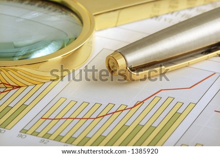 A pen and a magnifying glass  on a positive earning chart.