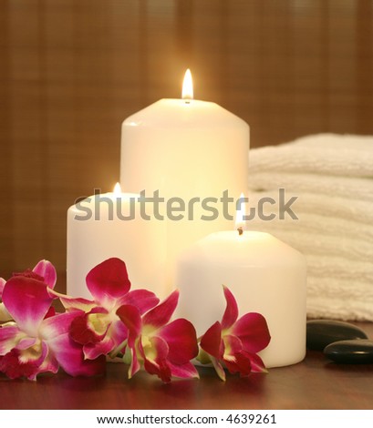 candles and orchids before towel in front of bamboo strip curtain--spa objects to make mood relaxing