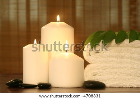 candles and towel with leaf and pebbles in front of bamboo strip curtain--spa objects to make mood relaxing
