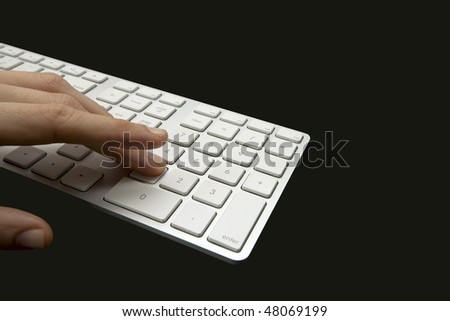 A female designer presses the number one on a white keyboard resting on a shiny black desk surface. Isolated on Black