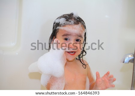 Baby taking a bubble bath with wet hair