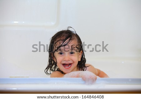 Happy baby taking a bubble bath laughing with wet hair