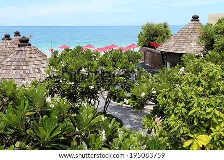 tropical landscape with flowering trees and houses on the sea