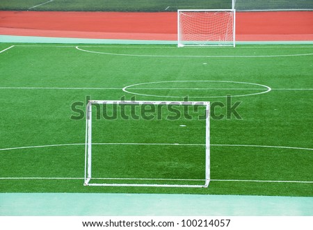 Empty soccer field with goal posts and light poles.