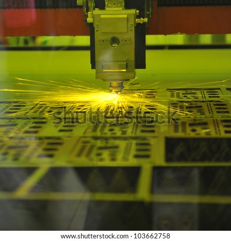 Industrial laser cutter with sparks.