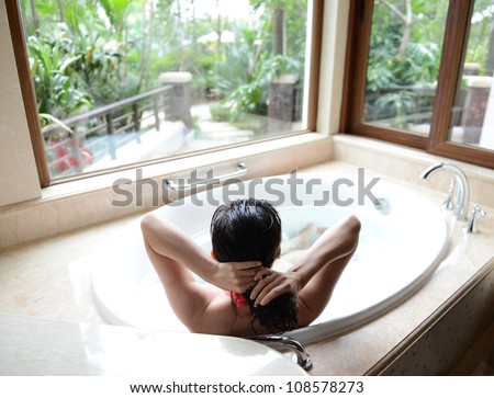 young woman in bathtub with a beautiful view outside the window.