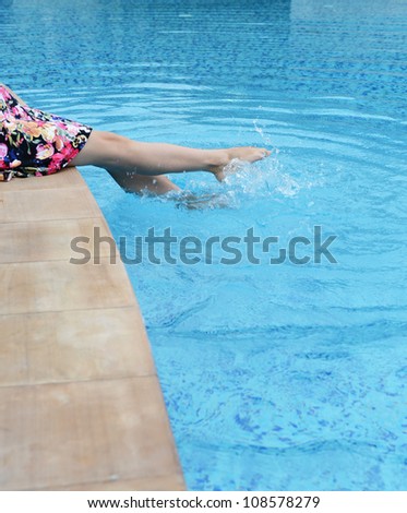 female feet in the pool making splashes.
