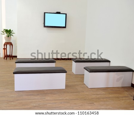 Hospital or clinic waiting room with stools and flat screen TV.