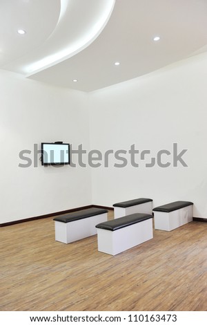 Hospital or clinic waiting room with stools and flat screen TV.