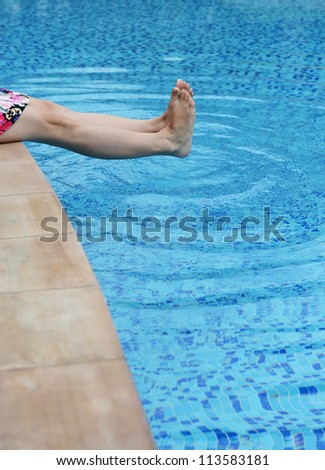 female feet in the pool making splashes.