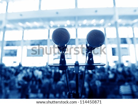 Closeup microphone in auditorium with people.