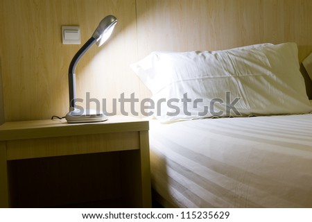 Close up of a bed with white sheets and a cozy lamp