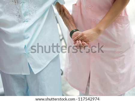 Young girl\'s hand touches and holds an old woman\'s wrinkled hands.