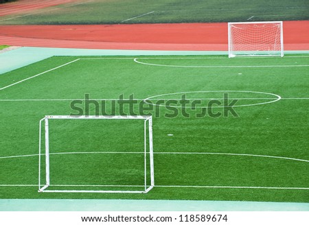 Empty soccer field with goal posts and light poles.