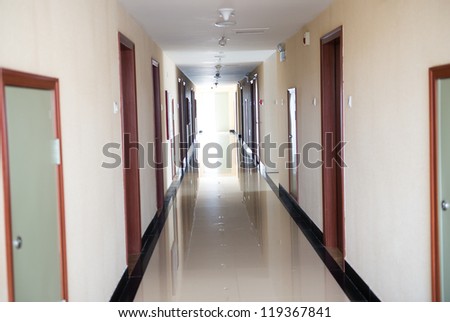 Empty long hotel corridor with doors.
