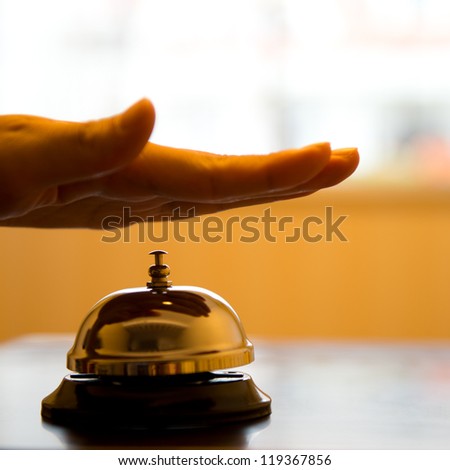 Hand ringing in service bell on wooden table.