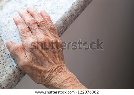 Senior woman\'s wrinkled hand near the window.